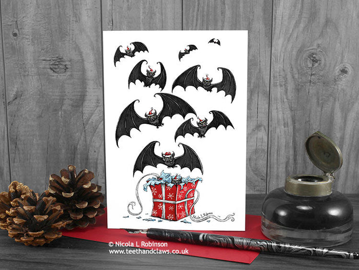 Gothic Bats Christmas Card, front view, featuring my original pen and ink illustration of bats. The card is standing on a red envelope, shown at an angle. © Nicola L Robinson | Teeth and Claws