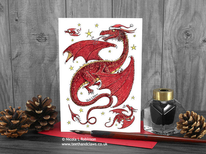 Dragon Christmas card, front view, featuring my original pen and ink festive red dragon illustration. The card is standing on a red envelope, shown at an angle. © Nicola L Robinson | Teeth and Claws