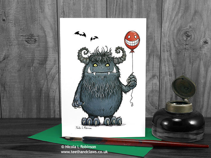 Monster greeting card, front view, featuring my original pen and ink illustration of a big hairy monster. The card is standing on a green envelope, shown at an angle. Design and illustration © Nicola L Robinson | Teeth and Claws