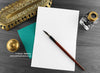 British shorthair cat greeting card, shown open and flat with blank inside, on a teal envelope, alongside vintage Victorian pen and writing desk accessories. Design and illustration © Nicola L Robinson | Teeth and Claws