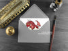 Red Dragon New Baby Card, shown lying flat, with my original pen and ink illustration of a baby red dragon, inside an open grey envelope. With vintage Victorian pen and writing desk accessories. Design and illustration © Nicola L Robinson | Teeth and Claws