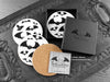 Set of four of my gothic bats coasters featuring my original pen and ink gothic bat illustrations, front view alongside a black gift box and card, with one coaster turned over to show the cork backing. Made in the UK. Design and illustration © Nicola L Robinson | Teeth and Claws.