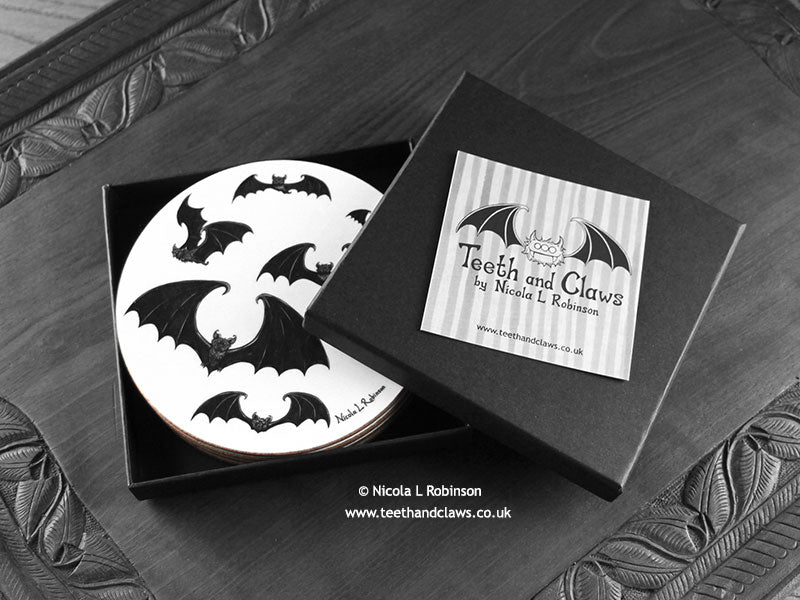 Set of four of my gothic bats coasters featuring my original pen and ink gothic bat illustrations, front view in an open black gift box with card. Made in the UK. Design and illustration © Nicola L Robinson | Teeth and Claws.