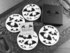 Set of four of my gothic bats coasters featuring my original pen and ink gothic bat illustrations, front view alongside a black gift box and card. Made in the UK. Design and illustration © Nicola L Robinson | Teeth and Claws