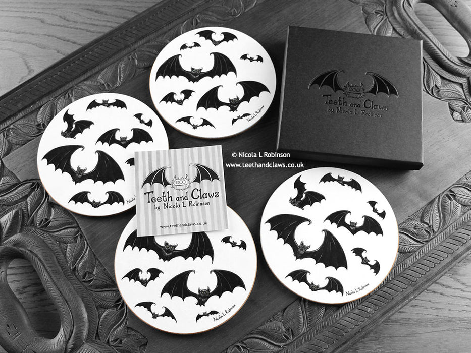 Set of four of my gothic bats coasters featuring my original pen and ink gothic bat illustrations, front view alongside a black gift box and card. Made in the UK. Design and illustration © Nicola L Robinson | Teeth and Claws