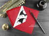 Gothic bats love card, shown lying flat, with my original pen and ink illustration of Gothic bats, inside an open red envelope. With vintage Victorian pen and writing desk accessories. Design and illustration © Nicola L Robinson | Teeth and Claws
