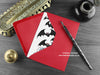 Gothic Bats Christmas Card, shown lying flat, with my original pen and ink illustration of festive bats, inside an open red envelope. With vintage Victorian pen and writing desk accessories. Design and illustration © Nicola L Robinson | Teeth and Claws