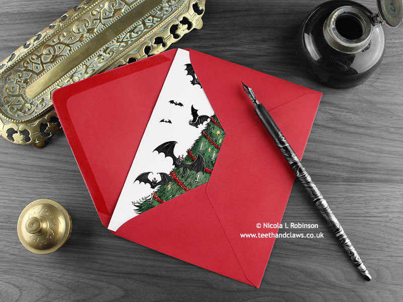 Gothic Bats Christmas card with my original pen and ink illustration of a Gothic Christmas tree, inside an open red envelope. With vintage Victorian pen and writing desk accessories. Design and illustration © Nicola L Robinson | Teeth and Claws