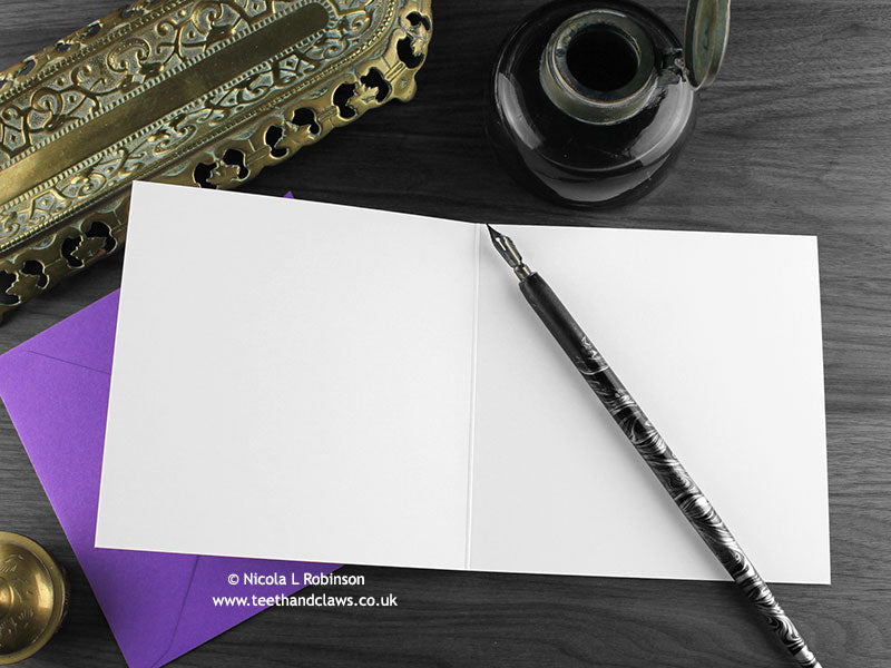 Gothic Bat Mother’s Day, New Baby Card, shown open and flat with blank inside, on a purple envelope, alongside vintage Victorian pen and writing desk accessories. Design and illustration © Nicola L Robinson | Teeth and Claws