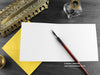 Bee Greeting card, shown open and flat with blank inside, on a yellow envelope, alongside vintage Victorian pen and writing desk accessories. Design and illustration © Nicola L Robinson | Teeth and Claws