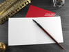 Cats Christmas card, shown open and flat with blank inside, on a red envelope, alongside vintage Victorian pen and writing desk accessories. Design and illustration © Nicola L Robinson | Teeth and Claws