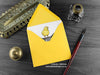Cat and chick greeting card, shown lying flat, with my original pen and ink illustration of a cat and chick, inside an open yellow envelope. With vintage Victorian pen and writing desk accessories. Design and illustration © Nicola L Robinson | Teeth and Claws