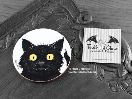 Black Cat Coaster featuring my original pen and ink illustration of a black cat face, front view alongside one of my branded cards. Made in the UK. Design and illustration © Nicola L Robinson | Teeth and Claws.