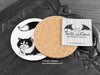 Black and White Cat Coaster featuring my original pen and ink illustration of a black and white cat, back view showing the cork backing, alongside one of my branded cards. Made in the UK. Design and illustration © Nicola L Robinson | Teeth and Claws.