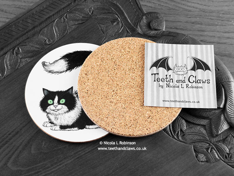 Black and White Cat Coaster featuring my original pen and ink illustration of a black and white cat, back view showing the cork backing, alongside one of my branded cards. Made in the UK. Design and illustration © Nicola L Robinson | Teeth and Claws.