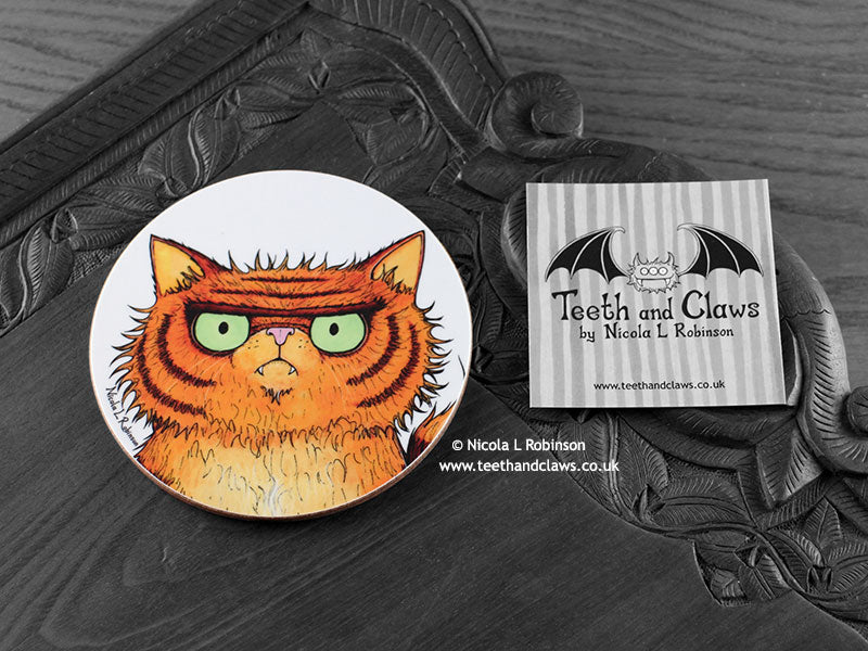 Persian Cat Coaster featuring my original pen and ink illustration of an orange Persian cat face, front view alongside one of my branded cards. Made in the UK. Design and illustration © Nicola L Robinson | Teeth and Claws.