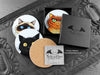 Set of four of my cat coasters featuring my original pen and ink cat illustrations, front view alongside a black gift box and card, with one coaster turned over to show the cork backing. Made in the UK. Design and illustration © Nicola L Robinson | Teeth and Claws.