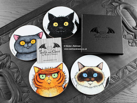 Set of four of my cat coasters featuring my original pen and ink cat illustrations, front view alongside a black gift box and card. Made in the UK. Design and illustration © Nicola L Robinson | Teeth and Claws.