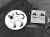 Siamese Cat Coaster featuring my original pen and ink illustration of a Siamese cat, front view alongside one of my branded cards. Made in the UK. Design and illustration © Nicola L Robinson | Teeth and Claws.