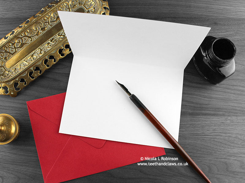 Cat love card, shown open and flat with blank inside, on a red envelope, alongside vintage Victorian pen and writing desk accessories. Design and illustration © Nicola L Robinson | Teeth and Claws