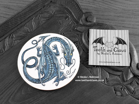 Blue Dragon Coaster featuring my original pen and ink illustration of a blue dragon, front view alongside one of my branded cards. Made in the UK. Design and illustration © Nicola L Robinson | Teeth and Claws.