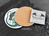 Green Dragon Coaster featuring my original pen and ink illustration of a green dragon, back view showing the cork backing, alongside one of my branded cards. Made in the UK. Design and illustration © Nicola L Robinson | Teeth and Claws.