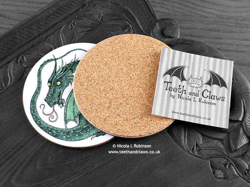 Green Dragon Coaster featuring my original pen and ink illustration of a green dragon, back view showing the cork backing, alongside one of my branded cards. Made in the UK. Design and illustration © Nicola L Robinson | Teeth and Claws.