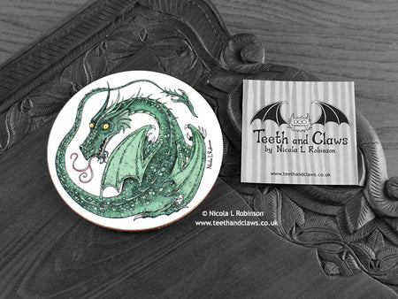 Green Dragon Coaster featuring my original pen and ink illustration of a green dragon, front view alongside one of my branded cards. Made in the UK. Design and illustration © Nicola L Robinson | Teeth and Claws.