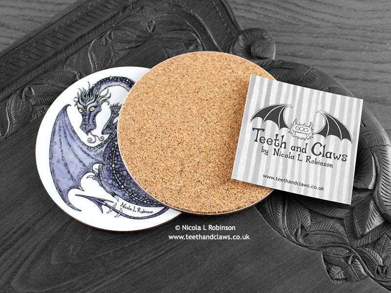 Purple Dragon Coaster featuring my original pen and ink illustration of a purple dragon, back view showing the cork backing, alongside one of my branded cards. Made in the UK. Design and illustration © Nicola L Robinson | Teeth and Claws.