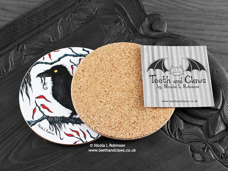 Crow Coaster featuring my original pen and ink illustration of a crow, back view showing the cork backing, alongside one of my branded cards. Made in the UK. Design and illustration © Nicola L Robinson | Teeth and Claws.