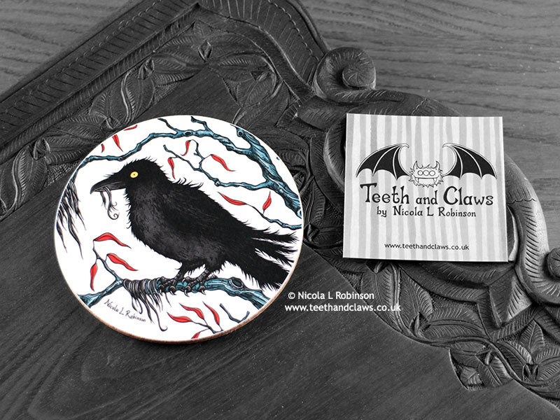 Crow Coaster featuring my original pen and ink illustration of a crow, front view alongside one of my branded cards. Made in the UK. Design and illustration © Nicola L Robinson | Teeth and Claws.