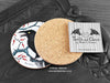 Crow Coaster featuring my original pen and ink illustration of a crow, back view showing the cork backing, alongside one of my branded cards. Made in the UK. Design and illustration © Nicola L Robinson | Teeth and Claws.