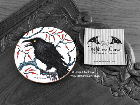 Crow Coaster featuring my original pen and ink illustration of a crow, front view alongside one of my branded cards. Made in the UK. Design and illustration © Nicola L Robinson | Teeth and Claws.