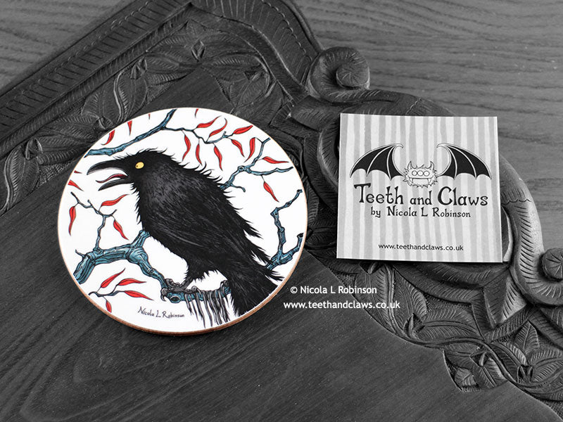 Crow Coaster featuring my original pen and ink illustration of a crow, front view alongside one of my branded cards. Made in the UK. Design and illustration © Nicola L Robinson | Teeth and Claws.