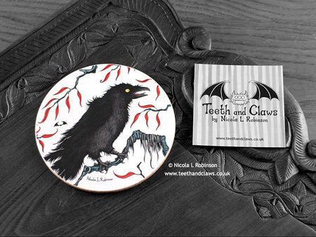 Crow Coaster featuring my original pen and ink illustration of a crow, front view alongside one of my branded cards. Made in the UK. Design and illustration © Nicola L Robinson | Teeth and Claws.