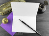 Crows birthday card, shown open and flat with blank inside, on a purple envelope, alongside vintage Victorian pen and writing desk accessories. Design and illustration © Nicola L Robinson | Teeth and Claws