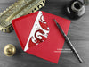 Two Dragons love card, shown lying flat, with my original pen and ink illustration of two red dragons, inside an open red envelope. With vintage Victorian pen and writing desk accessories. Design and illustration © Nicola L Robinson | Teeth and Claws