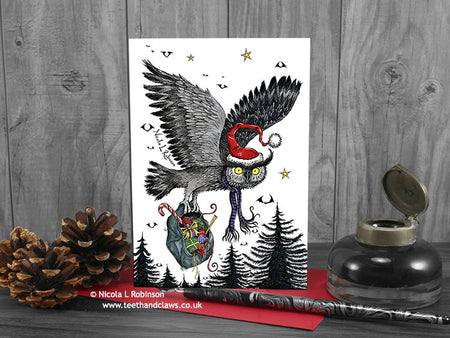 Flying Owl Christmas card, front view, featuring my original pen and ink owl illustration. The card is standing on a red envelope, shown at an angle. Design and illustration © Nicola L Robinson | Teeth and Claws