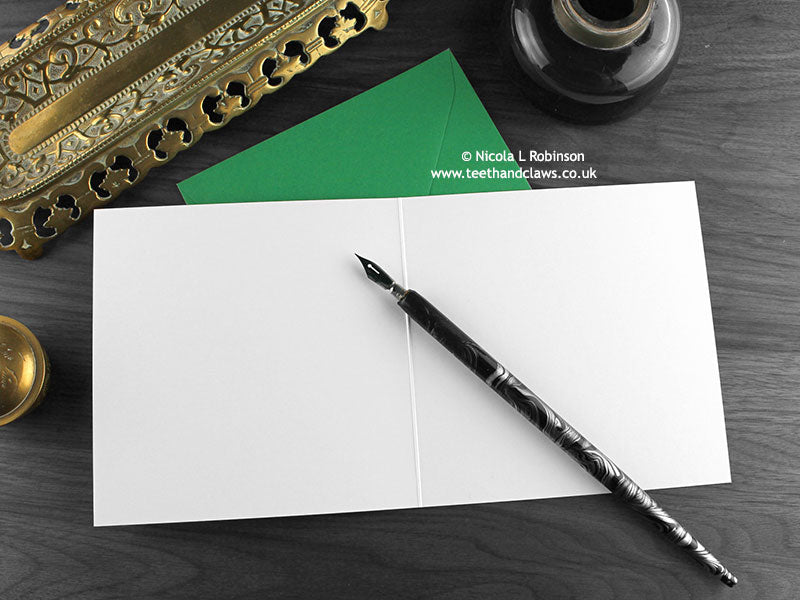 Monster Get Well Soon card, shown open and flat with blank inside, on a green envelope, alongside vintage Victorian pen and writing desk accessories. Design and illustration © Nicola L Robinson | Teeth and Claws