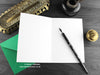 Monster greeting card, shown open and flat with blank inside, on a green envelope, alongside vintage Victorian pen and writing desk accessories. Design and illustration © Nicola L Robinson | Teeth and Claws