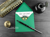 Monster Get Well Soon card, shown lying flat, with my original pen and ink illustration of a hairy monster, inside an open green envelope. With vintage Victorian pen and writing desk accessories. Design and illustration © Nicola L Robinson | Teeth and Claws