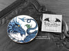 Blue Dragon Coaster featuring my original pen and ink illustration of a blue dragon, front view alongside one of my branded cards. Made in the UK. Design and illustration © Nicola L Robinson | Teeth and Claws.