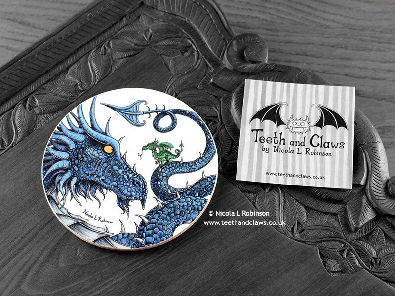Blue Dragon Coaster featuring my original pen and ink illustration of a blue dragon, front view alongside one of my branded cards. Made in the UK. Design and illustration © Nicola L Robinson | Teeth and Claws.