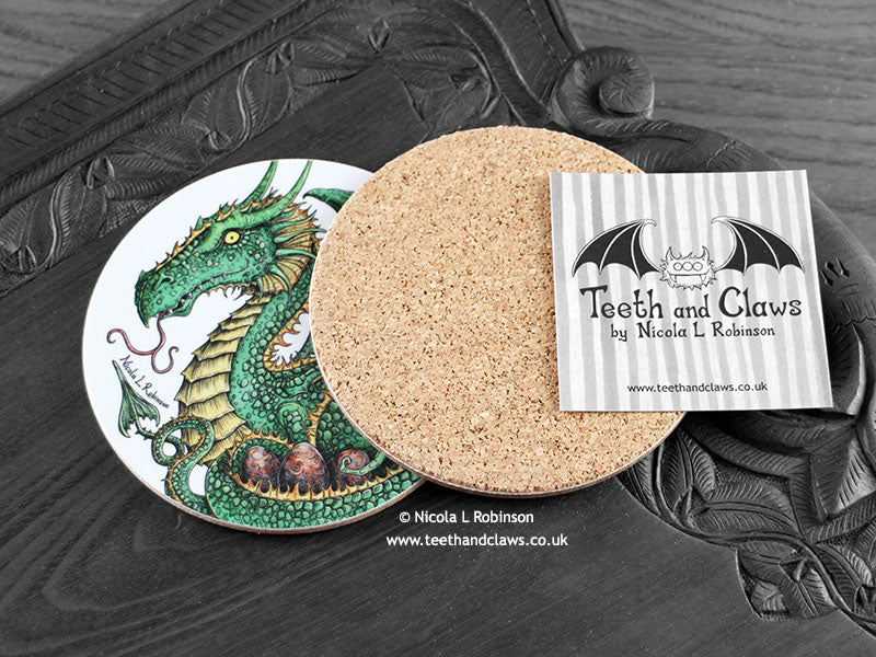 Green Dragon Coaster featuring my original pen and ink illustration of a green dragon, back view showing the cork backing, alongside one of my branded cards. Made in the UK. Design and illustration © Nicola L Robinson | Teeth and Claws.