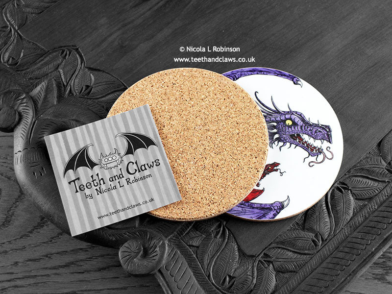 Purple Dragon Coaster featuring my original pen and ink illustration of a purple dragon, back view showing the cork backing, alongside one of my branded cards. Made in the UK. Design and illustration © Nicola L Robinson | Teeth and Claws.