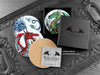 Set of four of my dragon coasters featuring my original pen and ink dragon illustrations, front view alongside a black gift box and card, with one coaster turned over to show the cork backing. Made in the UK. Design and illustration © Nicola L Robinson | Teeth and Claws.