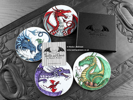 Set of four of my dragon coasters featuring my original pen and ink dragon illustrations, front view alongside a black gift box and card. Made in the UK. Design and illustration © Nicola L Robinson | Teeth and Claws.
