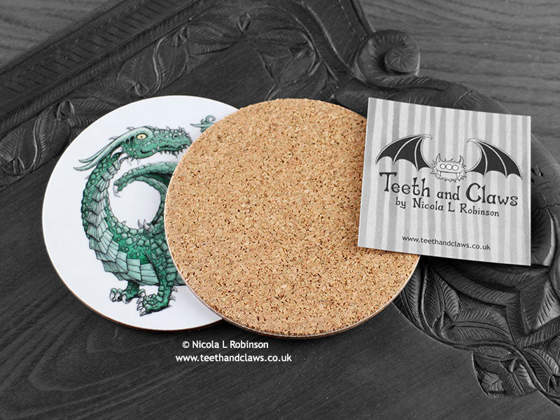 Green Dragon Coaster featuring my original pen and ink illustration of a green dragon, back view showing the cork backing, alongside one of my branded cards. Made in the UK. Design and illustration © Nicola L Robinson | Teeth and Claws.