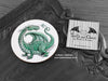 Green Dragon Coaster featuring my original pen and ink illustration of a green dragon, front view alongside one of my branded cards. Made in the UK. Design and illustration © Nicola L Robinson | Teeth and Claws.