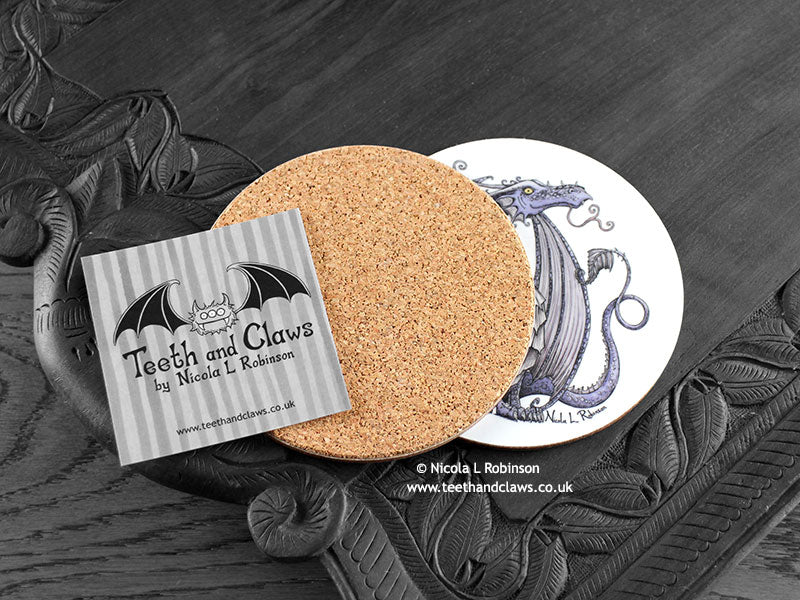 Lilac Dragon Coaster featuring my original pen and ink illustration of a purple dragon, back view showing the cork backing, alongside one of my branded cards. Made in the UK. Design and illustration © Nicola L Robinson | Teeth and Claws.